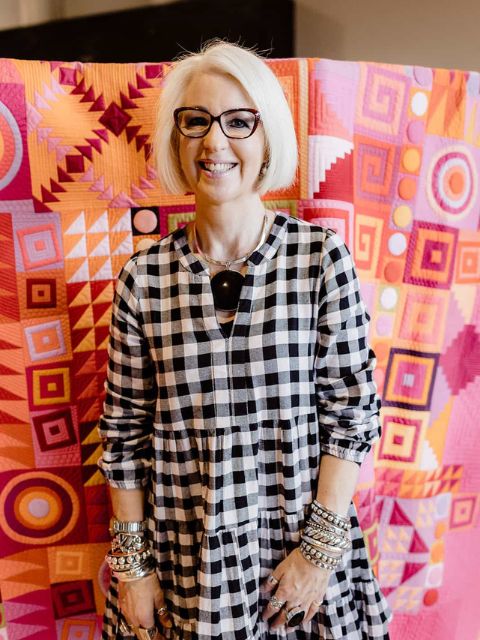 Photo of Penny Shapter in front of colourful quilt